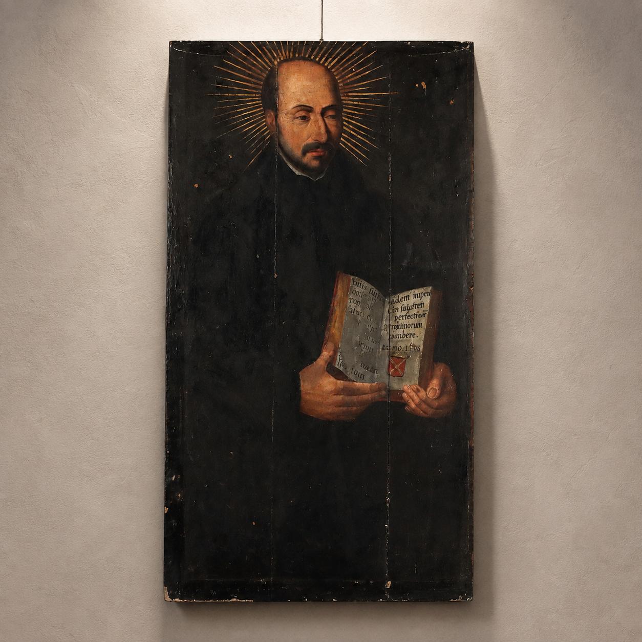 Antique religious oil painting on wood panel depicting a haloed saint in black robes holding an open book with Latin text, dark background, aged distressed finish