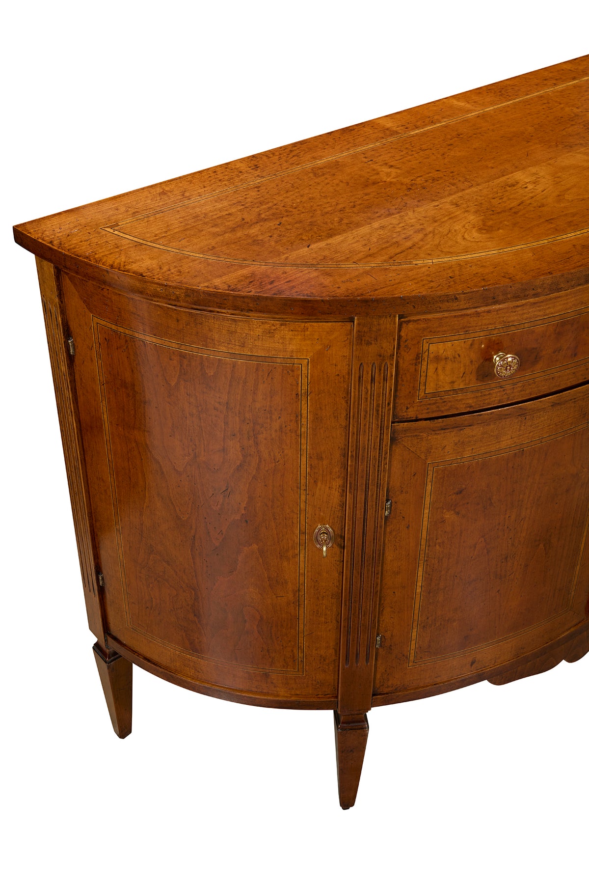 Curved wooden demilune cabinet in warm brown finish with two doors, one drawer, and decorative brass hardware on tapered legs
