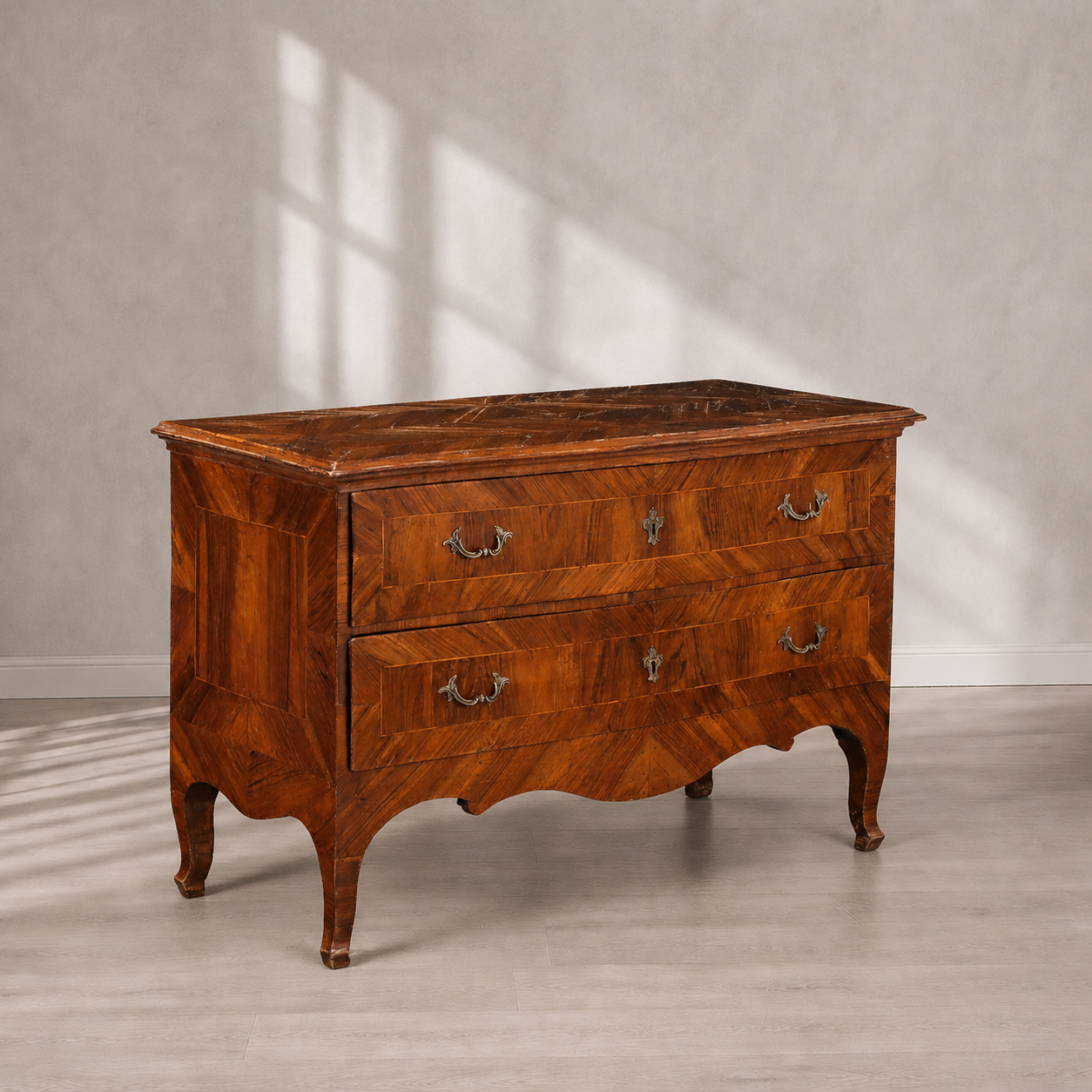 Antique Italian-style walnut commode with two drawers, herringbone parquetry veneer, ornate brass bail handles, serpentine apron, and elegant cabriole legs in warm honey-brown tones.
