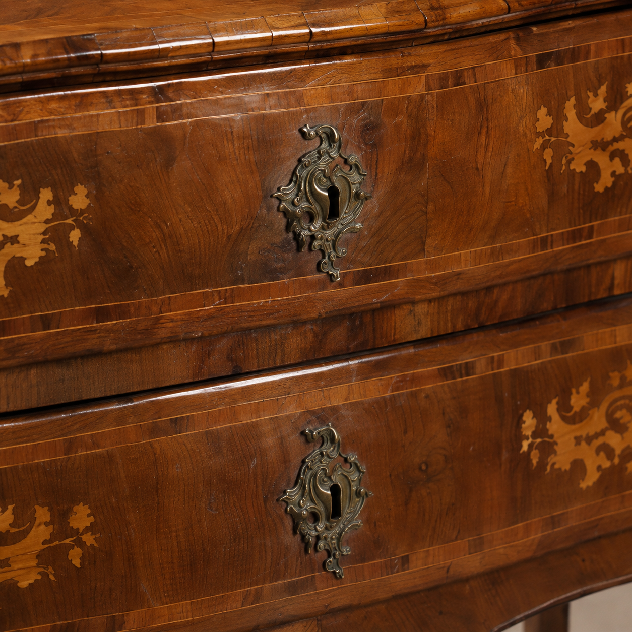 Antique walnut chest of drawers with intricate marquetry inlay, ornate brass escutcheon keyholes, crossbanding details, and rich warm brown tones in Baroque style.