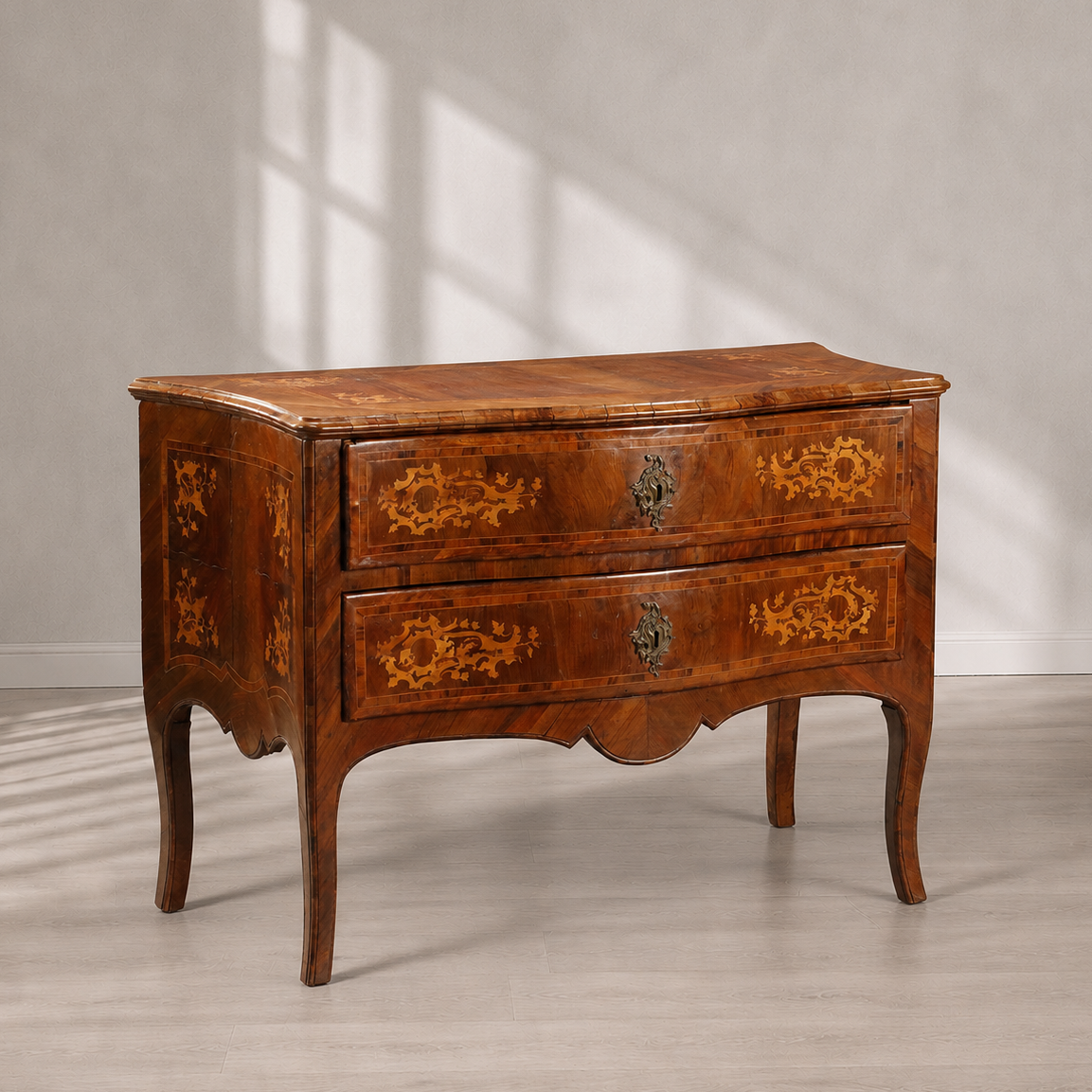 Antique walnut commode with two drawers featuring intricate marquetry inlay floral patterns, bronze escutcheon hardware, cabriole legs, and serpentine apron in warm brown tones.