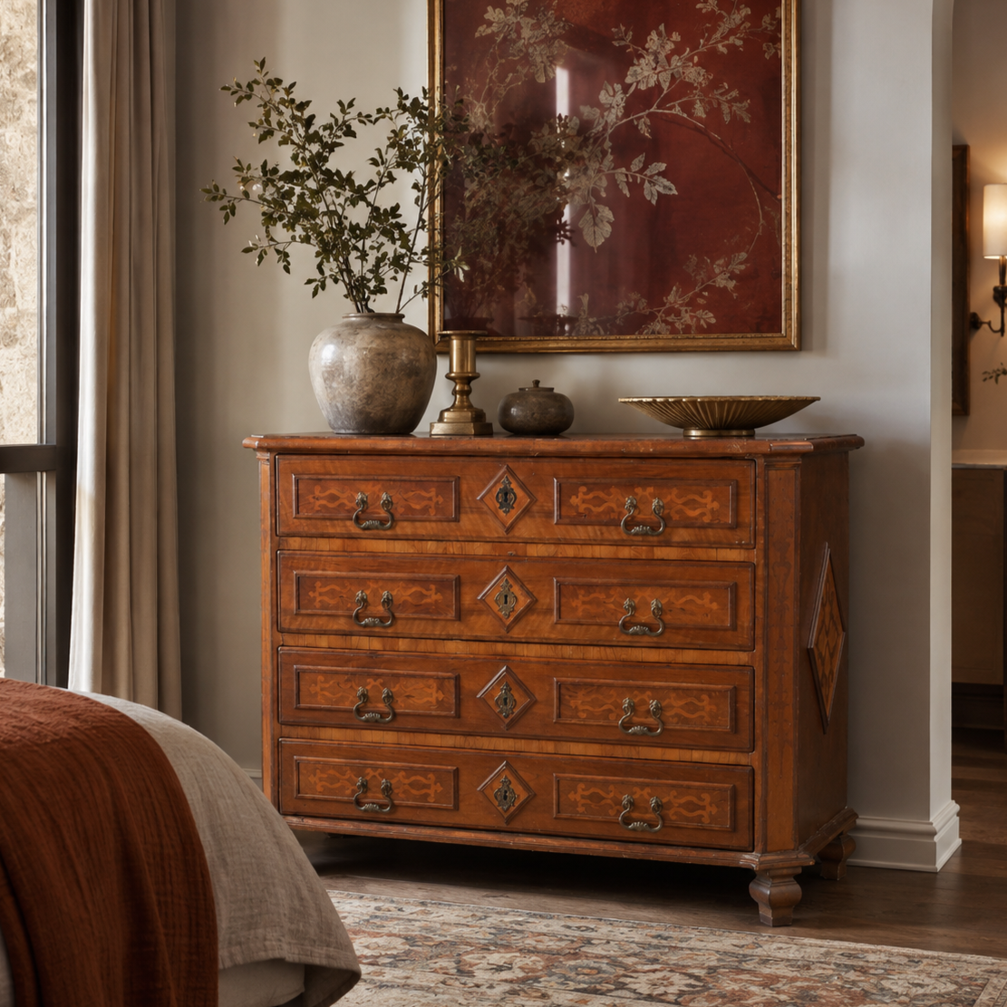 Antique-style 4-drawer wooden dresser with marquetry inlay, brass bail pulls, and diamond-shaped escutcheons in rich walnut brown finish, styled with vintage decor