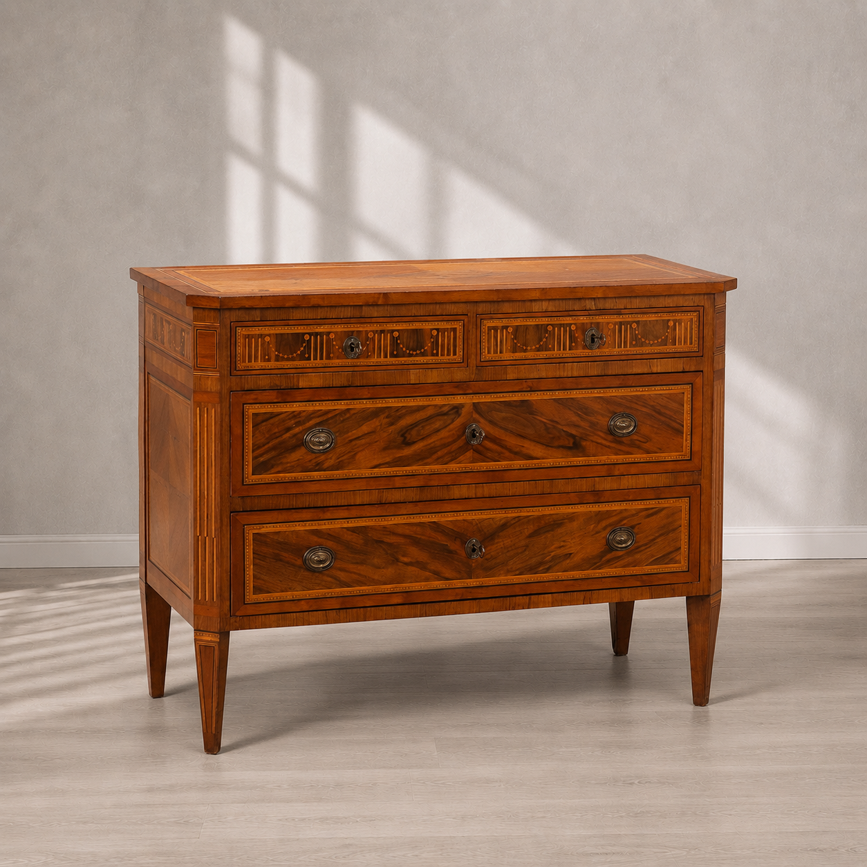 Antique-style walnut chest of drawers with marquetry inlay, four drawers, brass oval hardware, tapered legs, and rich warm brown wood grain detailing