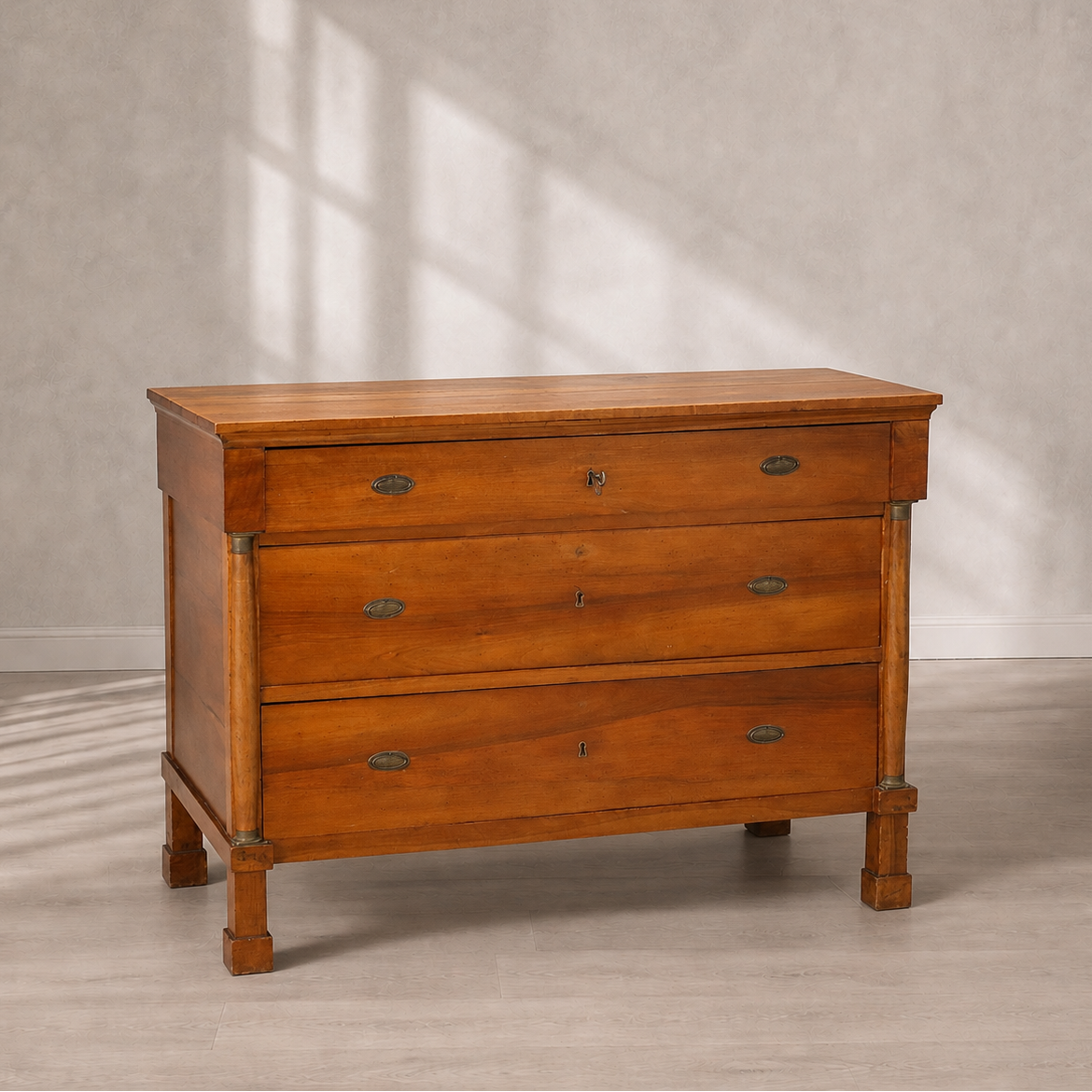 Antique-style cherry wood chest of drawers with three drawers, oval brass hardware pulls, keyhole escutcheons, column pilasters, and square tapered legs.