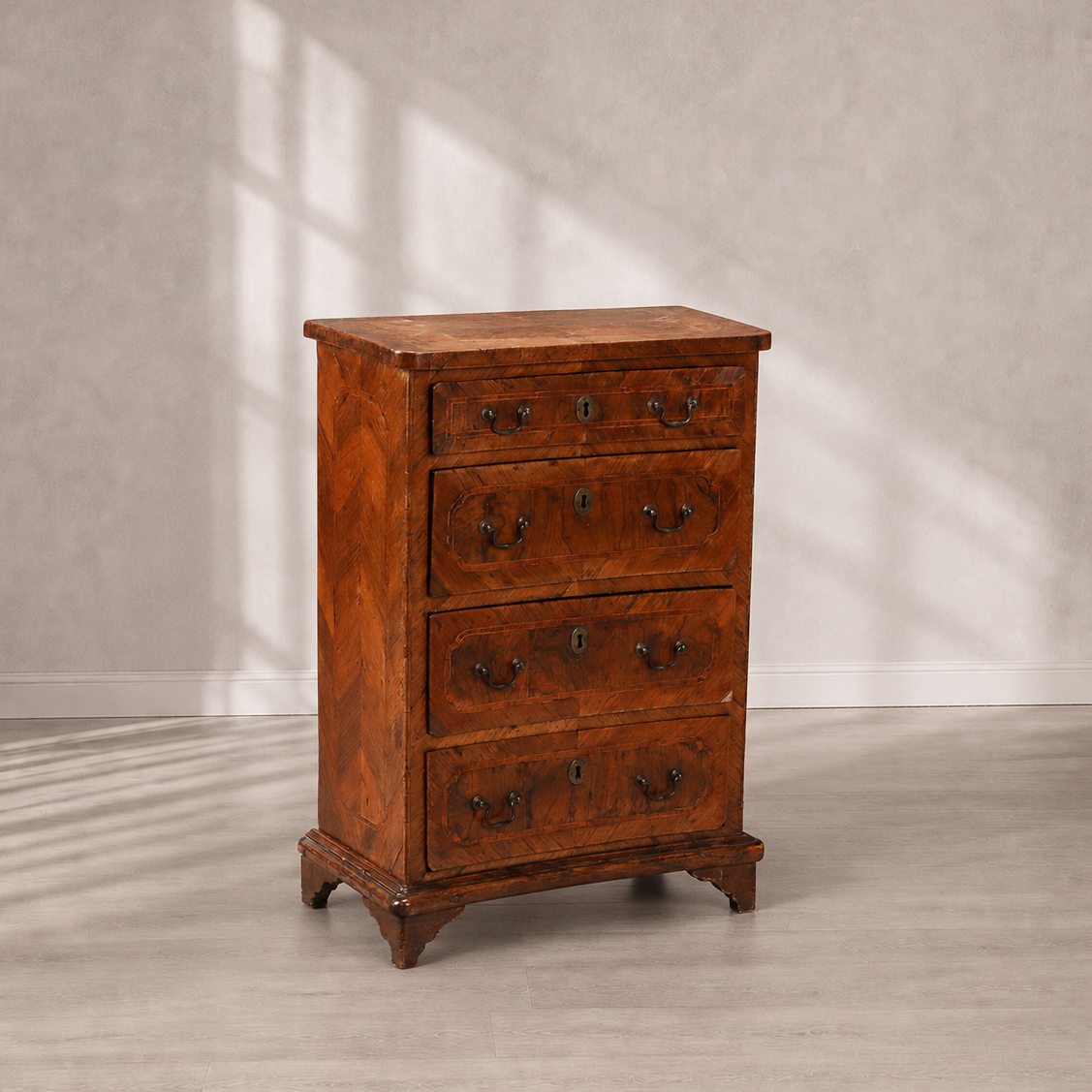 Antique walnut chest of drawers with parquetry veneer, four drawers, brass bail handles, keyhole escutcheons, and bracket feet in warm reddish-brown tones.