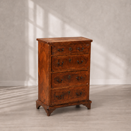 Antique walnut chest of drawers with parquetry veneer, four drawers, brass bail handles, keyhole escutcheons, and bracket feet in warm reddish-brown tones.