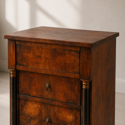 Antique Empire-style tall chest of drawers in rich walnut veneer with ebonized columns, gilt capitals, and lion head brass ring pulls, showing beautiful aged patina