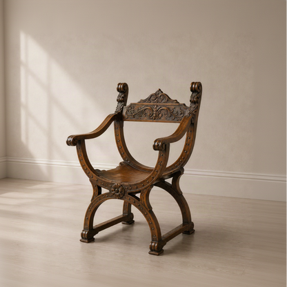 Antique-style dark walnut Dagobert throne chair with ornate carved scrollwork backrest, X-frame curved legs, studded leather seat, and scrolled armrests