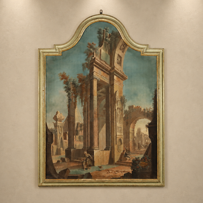Antique Italian capriccio painting in ornate silver-green carved wood frame with arched top, depicting Roman ruins with figures, columns, and classical archways.