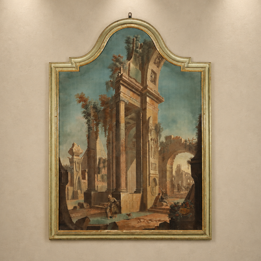 Antique Italian capriccio painting in ornate silver-green carved wood frame with arched top, depicting Roman ruins with figures, columns, and classical archways.