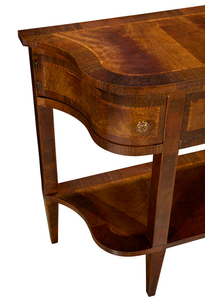 Elegant curved wooden console table with rich mahogany finish featuring decorative grain patterns, single drawer with ornate brass knob, lower shelf storage, and gracefully tapered legs