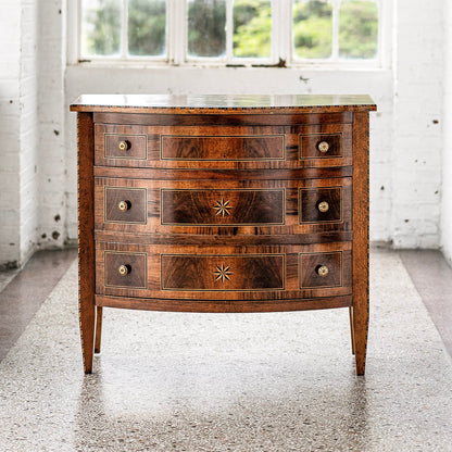 Antique-style walnut chest of drawers with three curved front drawers, decorative star inlays, brass hardware, and light wood string inlay trim on tapered legs