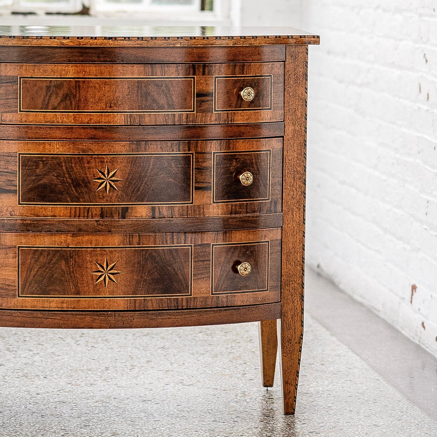 Traditional walnut chest with three drawers featuring decorative star inlays and brass knob hardware. Rich brown wood grain with light-colored trim details on tapered legs.