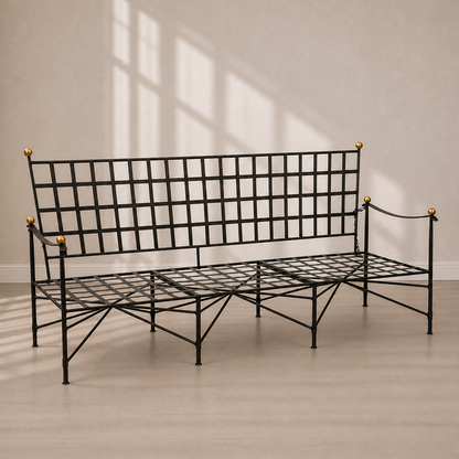 Black wrought iron garden bench with grid-pattern backrest and seat, decorative gold brass ball finials on corners, and crossed metal leg supports