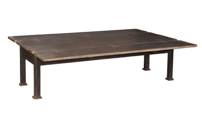 Rustic rectangular coffee table with weathered dark brown wooden plank top and black metal industrial-style legs with decorative feet, showing distressed finish and visible wood grain