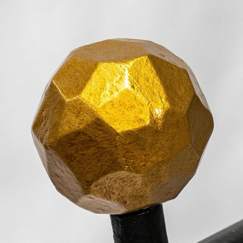 Faceted gold-painted decorative ball finial atop a black metal rod, featuring a multifaceted geometric design with warm metallic sheen and textured surface.