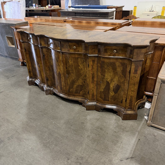 Traditional curved sideboard buffet in rich walnut wood with ornate burl wood veneer panels, featuring multiple cabinet doors, decorative carved legs, and scalloped edges