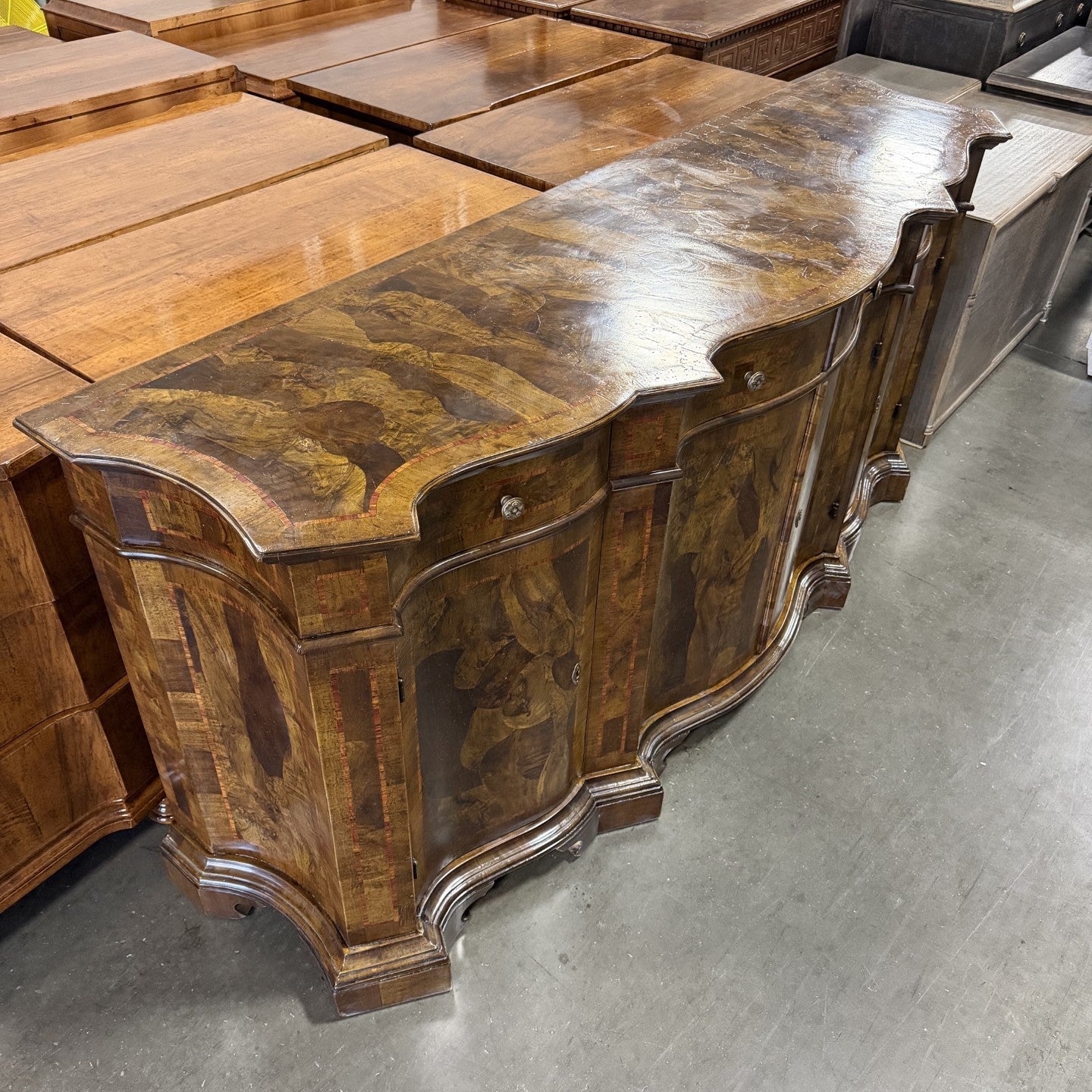 Traditional curved sideboard with rich walnut wood finish featuring intricate burl wood veneer panels, ornate curved edges, decorative hardware, and elegant stepped base molding