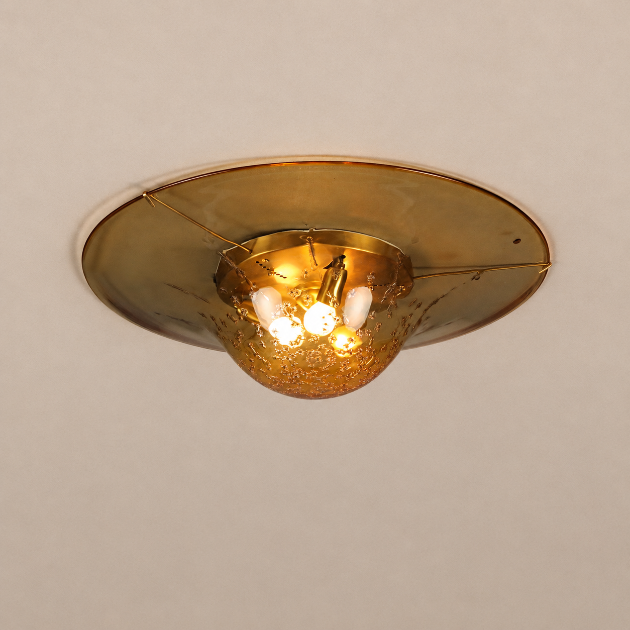 Vintage-style flush mount ceiling light with amber smoked glass disc shade and textured gold bowl housing four small bulbs, mounted on cream ceiling.