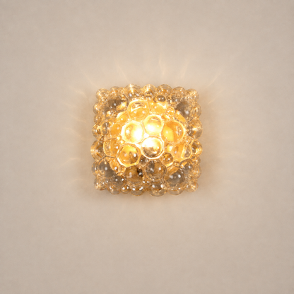 Square bubble glass wall sconce with warm amber glow, featuring textured clear glass spheres arranged in a honeycomb pattern, flush-mount mid-century modern light fixture