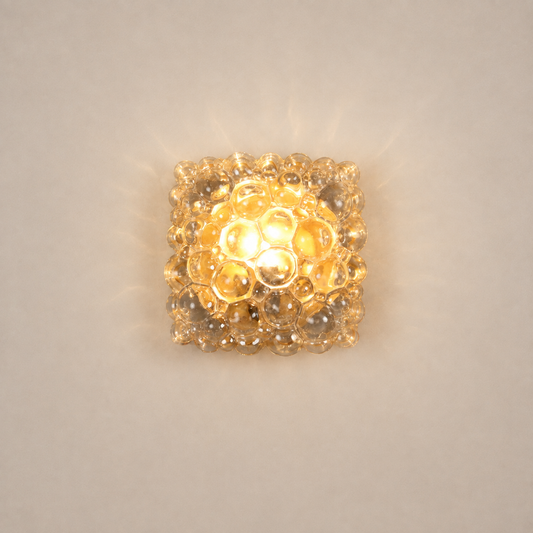 Square bubble glass wall sconce with warm amber glow, featuring textured clear glass spheres arranged in a honeycomb pattern, flush-mount mid-century modern light fixture