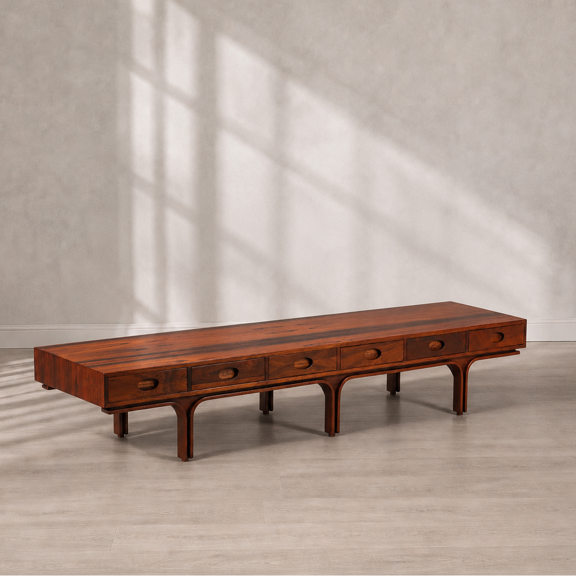 Mid-Century modern low-profile rosewood coffee table with five oval pull drawers, arched leg base, and rich warm brown grain finish, approximately 7 feet long.