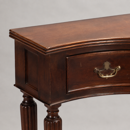 Traditional mahogany console table with curved serpentine front, single drawer with ornate brass bail pull hardware, reeded turned legs, and rich dark brown finish