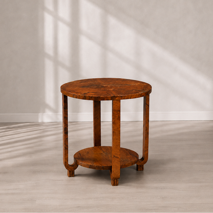 Art Deco round two-tier side table in warm burled walnut veneer with curved U-shaped legs, lower circular shelf, and rich amber-brown figural grain pattern.