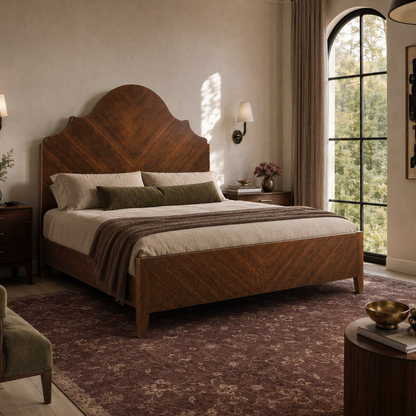Rich walnut-toned wood bed with arched chevron-patterned headboard, tapered legs, and low footboard in a warm transitional bedroom setting