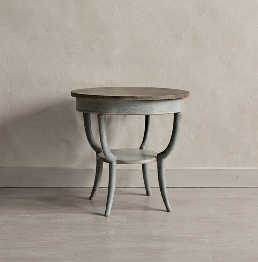 Round occasional table with weathered gray painted finish and curved legs. Features a darker wood top contrasting with the painted base in a vintage-inspired design.